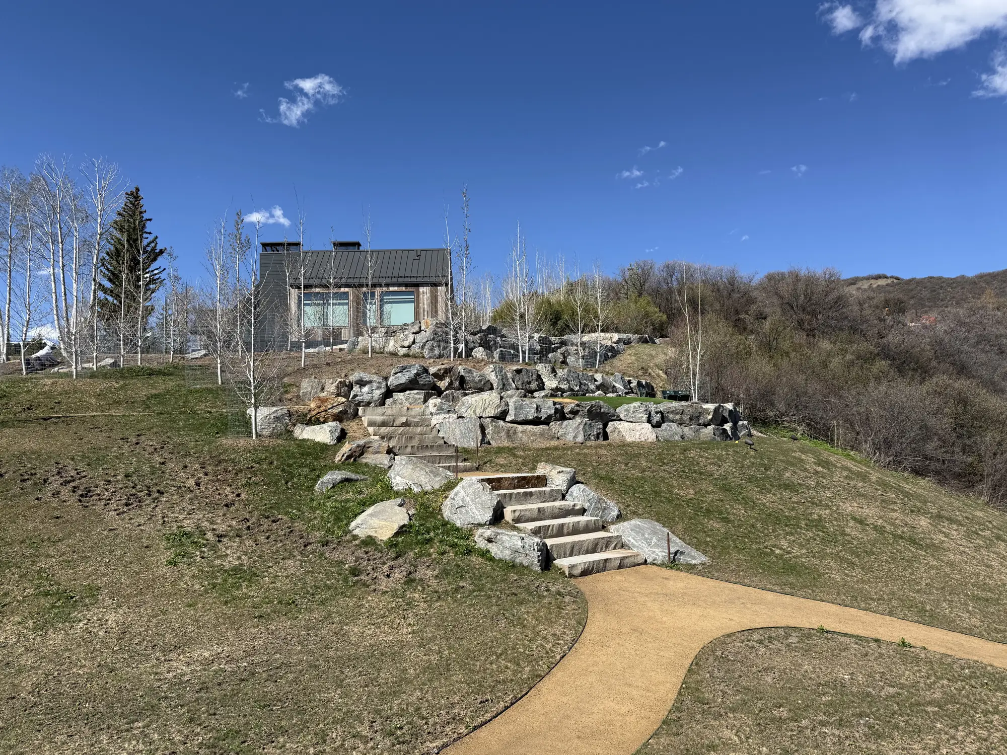 Terraced boulder retaining walls and cut stone steps on a hillside lot
