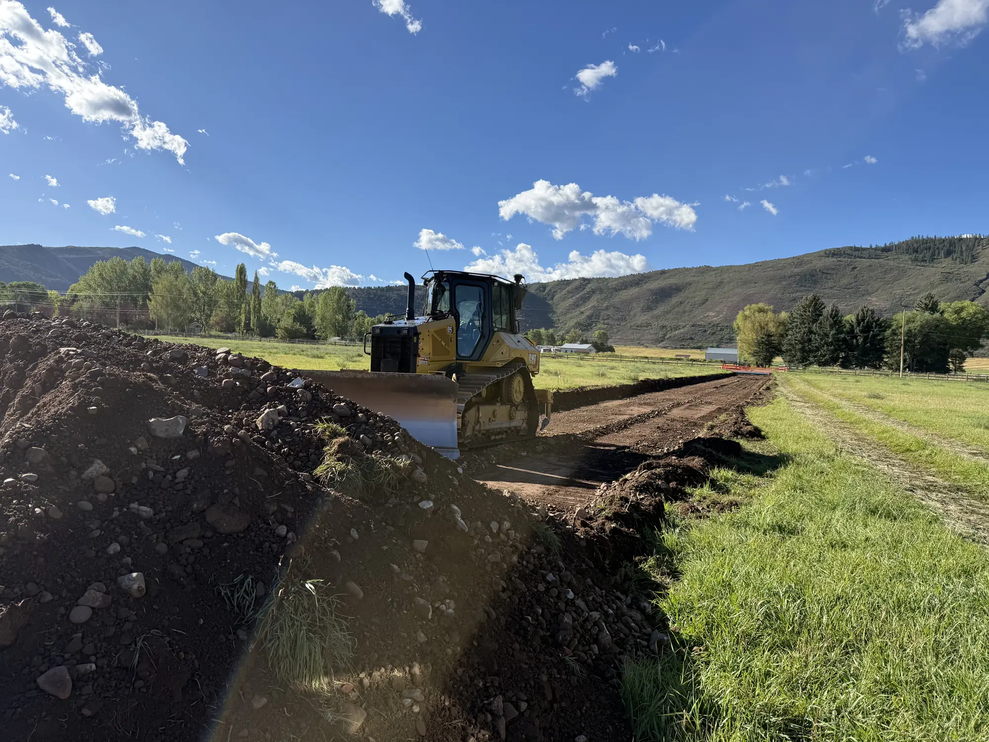 Dozer spreading and grading fill along a long cut on a commercial site