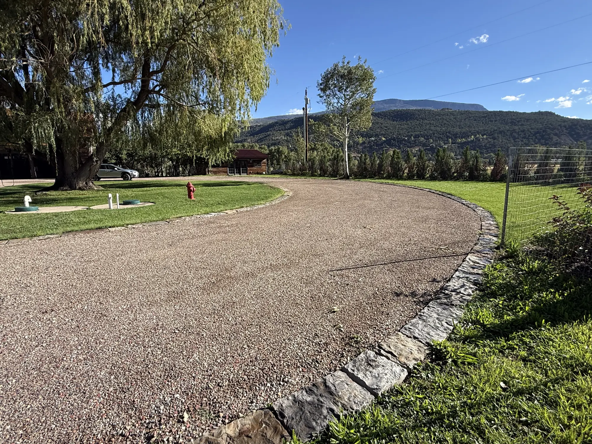Driveway edged in cut stone beside an irrigated lawn