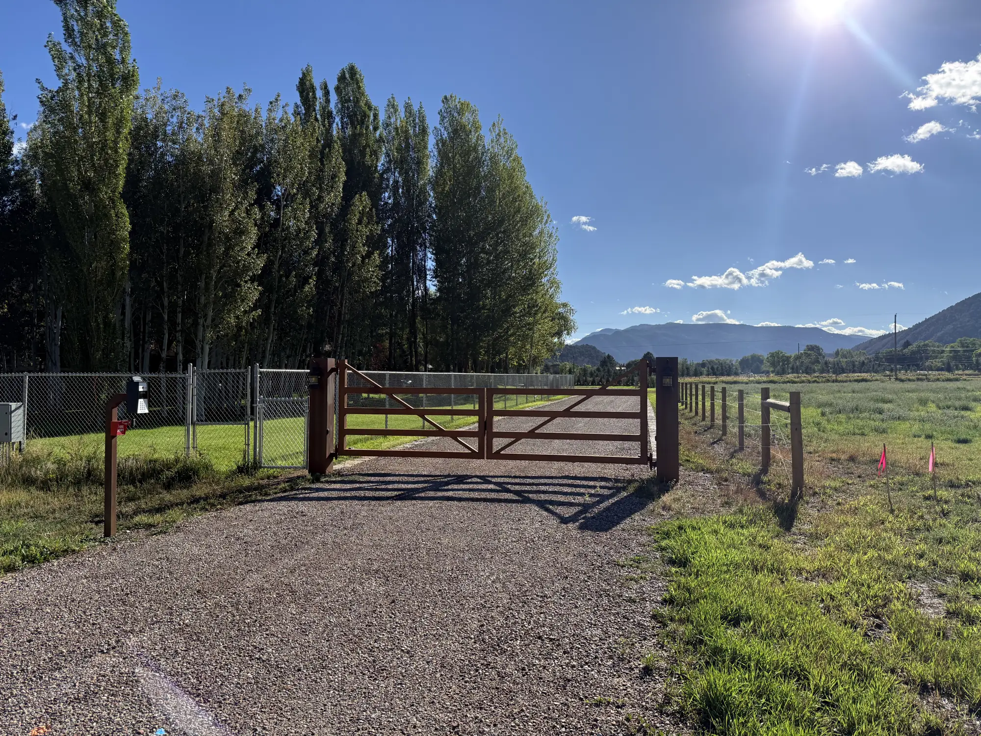 Finished gravel driveway with a steel gate and new fence line