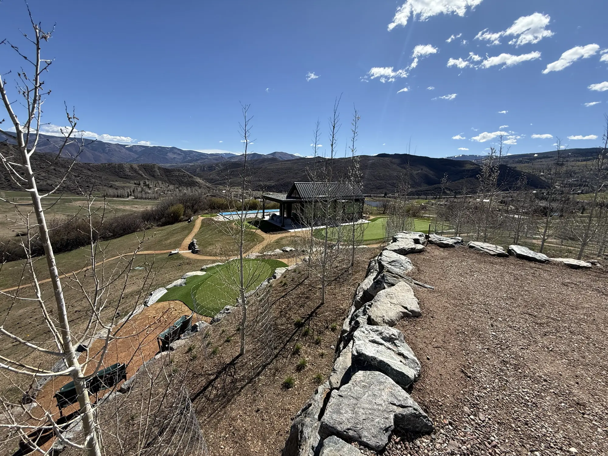 Boulder retaining wall holding a hilltop terrace above a valley