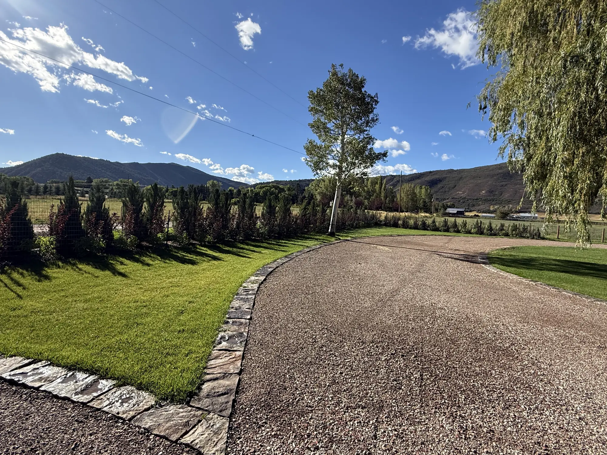 New lawn edged in cut stone with hedge planting along a fence line