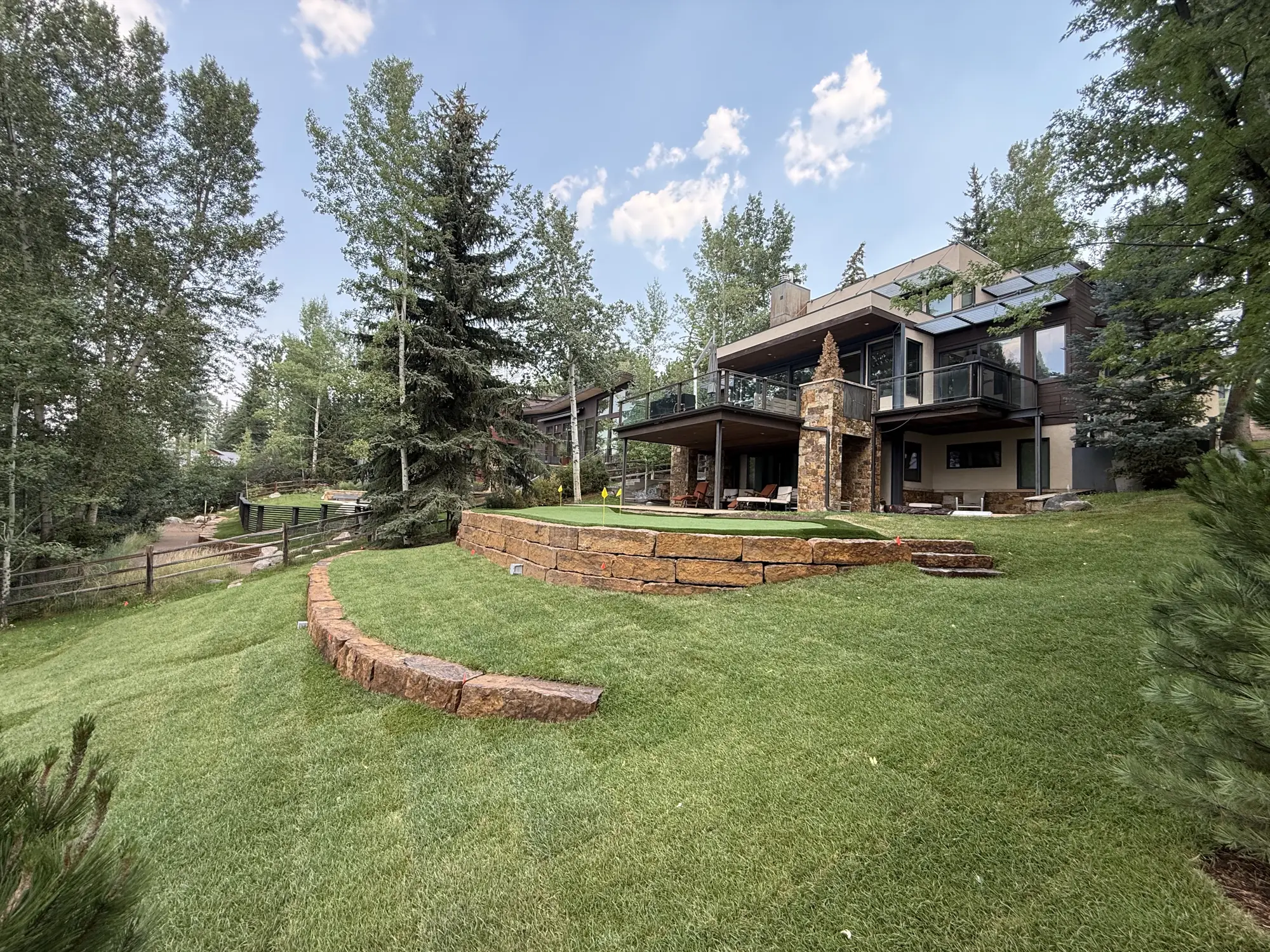 Finished Ridgeline landscape: new lawn, sandstone block retaining wall and curved stone edging below a contemporary mountain home
